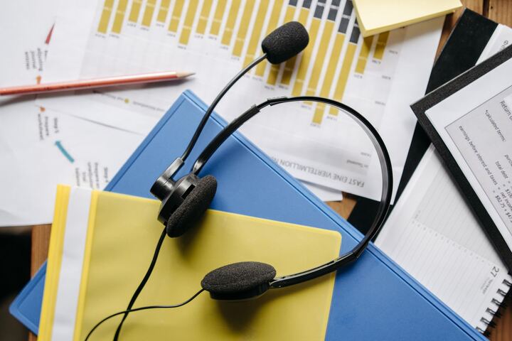 A wired headset resting on office folders and paperwork
