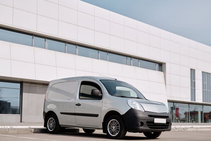 An unmarked compact van parked outside a commercial building